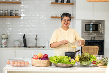 Senior Asian woman elder happy living in home kitchen. Elderly woman cooking in a kitchen. Happy mature woman in the kitchen,  Active seniors. Older people relationship and activity
