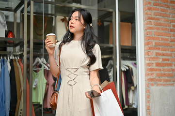 A charming Asian girl enjoys her shopping day alone in the city, carrying her shopping bags