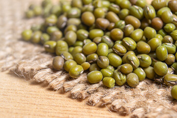 Mung beans on top of a jute fabric on wood surface