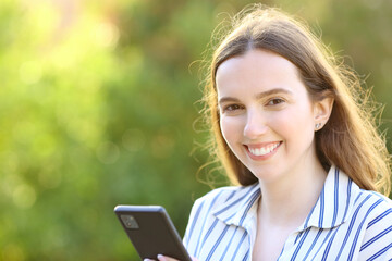 Happy woman holds phone and looks at you