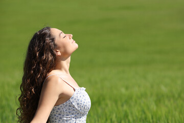 Woman breathing fresh air on green field bacground