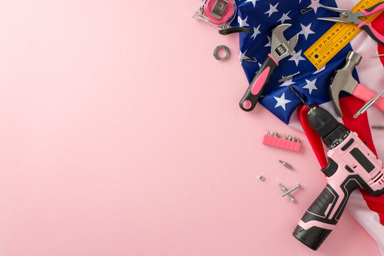 Paying tribute to female workers on Labor Day. Top view image of an American flag accompanied by building tools on a pink background. Perfect for advertisements or text placement