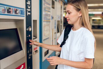 Fototapeta na wymiar Long-haired blonde young girl near ATM in the business center