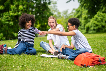 Fototapeta premium Blonde girl and two african american kids spending time together int he park