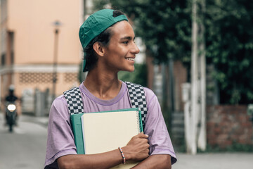 student walking down the street with books and backpack