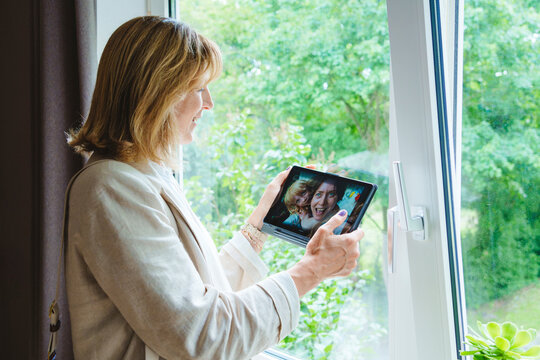 Mature woman talking on video call with daughter and granddaughter through tablet PC