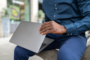 Dark-skinned man with a laptop working outside