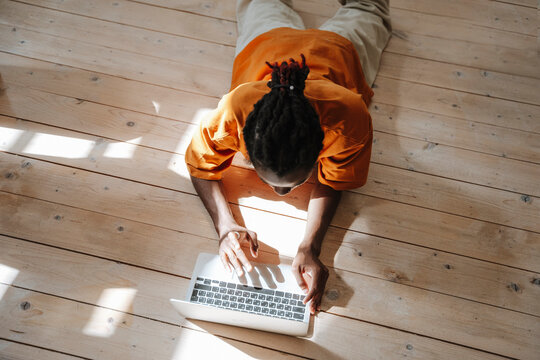 Freelancer working with laptop lying on floor at home