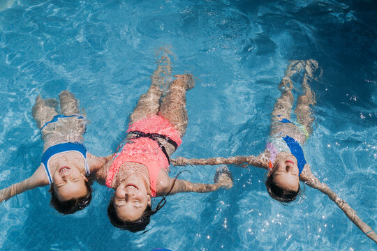 Carefree friends with arms outstretched swimming in pool