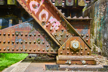 Obraz na płótnie Canvas Rusty metal rivets on railroad bridge side view and pink graffiti with corroding blue metal