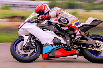 A motorcycle racer is driving fast on a motorcycle track.