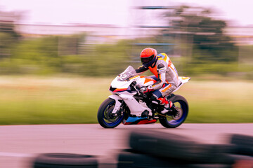 A motorcycle racer is driving fast on a motorcycle track.
