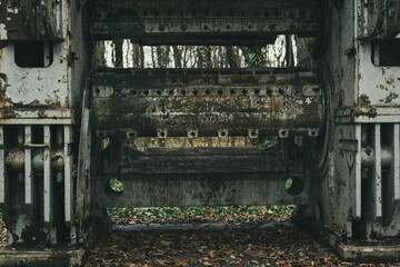 Detail of an old abandoned and rusted sheet metal working machine in the forest. Iron and steel production. Industrial history machine. 