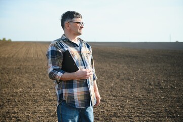 The farmer works on the ground. Male farmer on a plowed field, planting cereals in the spring in the ground. Agricultural business concept. Growing food, vegetables.