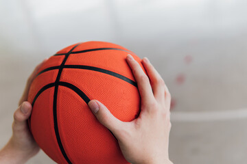 Hands holding a basketball in a court