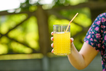 Dziewczyna trzymająca szklankę zimnego soku pomarańczowego  - obrazy, fototapety, plakaty