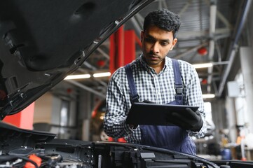 Fototapeta na wymiar service, repair and profession concept - indian mechanic at car service