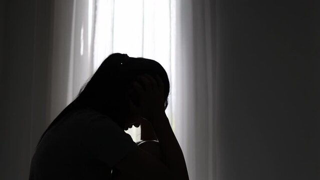 silhouette of a sad woman in the dark domestic violence Family problems. Stress. Violence. Depression and suicide concept.