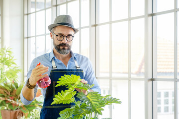 A senior man or grandfather with a mustache enjoys gardening for the tree at home after retirement