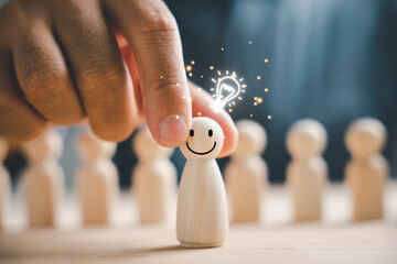 A wooden figure holds a glowing light bulb, representing creative thinking and inspiration....
