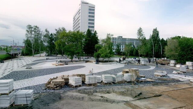 Stone slabs and construction debris laying around park at daytime. Workers checking and inspecting newly built park in windy weather