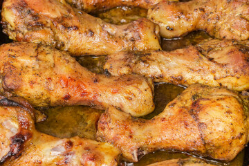 Baked chicken legs on tray, close-up in selective focus