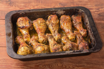 Baked chicken legs on metal oven-tray on rustic table