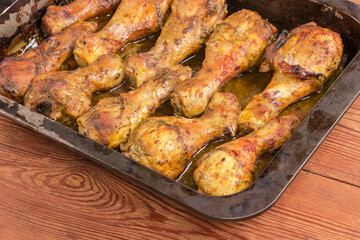 Baked chicken legs on metal oven-tray on rustic table