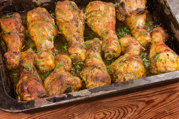 Baked chicken legs on metal baking sheet on rustic table