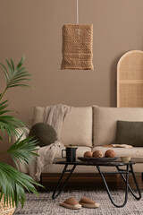 Creative composition of boho living room interior with beige sofa, black round coffee table, boho lamp, partition wall, plaid, colorful basket on wall and personal accessories. Home decor. Template. © FollowTheFlow