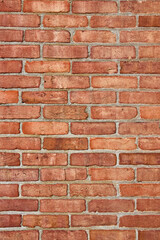 Vertical clean but faded red brick wall textured and faded by time