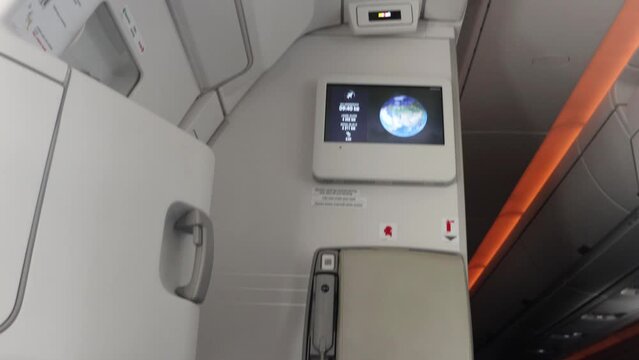 View of the flying plane on passenger monitor with a change view on the monitor on a wall