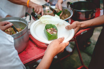 The hands of hungry people reach out for free food from community volunteers.