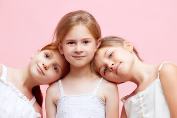 Portrait of beautiful little girls, children posing together against pink studio background. Well-being, care free time. Concept of skincare, childhood, cosmetology and health, beauty, ad