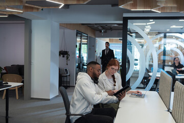 In a modern office African American young businessman and his businesswoman colleague, with her striking orange hair, engage in collaborative problem-solving sessions