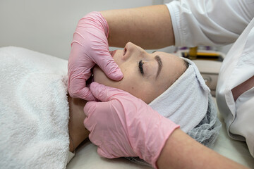 Obraz na płótnie Canvas Beautician doing facial massage female client at spa