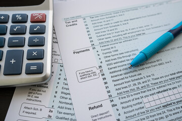 1040 tax form with pen and calculator on office desk