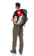 Back view full-length portrait of trekker with a backpack and flag of Switzerland isolated on white background. Thirty years old man in black T-shirt posing in studio.