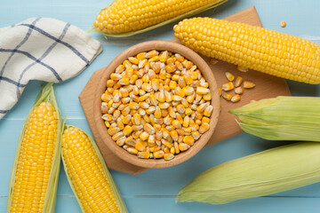 Dry corn with fresh cobs on wooden background, top view