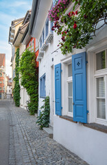 Fototapeta na wymiar white house with blue windows and hanging plants in idyllic village
