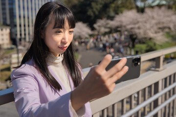 A portrait of selfie by Japanese woman behind cherry blossom bust shot