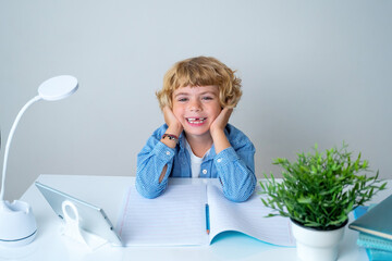 Elementary school smiling boy girl sitting at desk, studying writing book and tablet at class home looking at camera. Copy space for advertising blank concept. Back to school. 