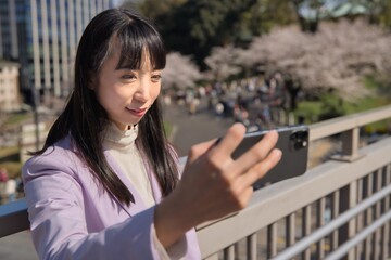 Fototapeta premium A portrait of selfie by Japanese woman behind cherry blossom bust shot