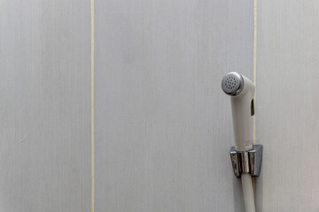 White bidet shower hanging on the white ceramic wall. Toilet shower for washing external genital.