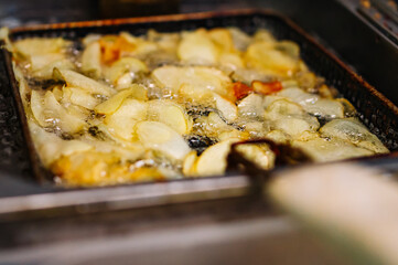 frying potato chips in hot oil on kitchen