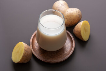 Concept of alternative milk. Glass with potato milk on brown background.