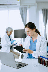 Two scientist or medical technician working, having a medical discuss meeting with an Asian senior female scientist supervisor in the laboratory with online reading, test samples and innovation