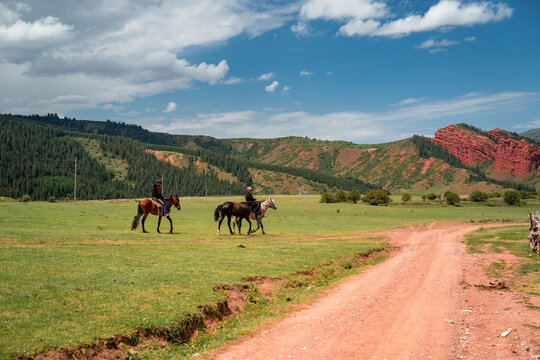 Two locals on horseback traverse the stunning landscapes of this picturesque Kyrgyz destination. Experience the wonders of Jety Oguz gorge  a true equestrian's dream and a nature lover's haven, 