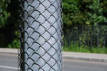The concrete pole is covered with a metal mesh from posting paper ads