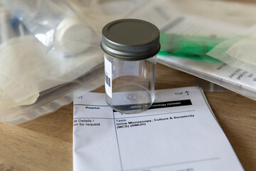 A sample container and a medical form for a Urine Microscopy test.